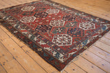 Distressed end of Baktiari rug, showcasing artistic aubergine border and hexagonal panels.