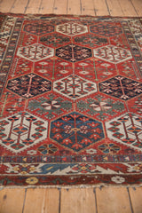 Distressed Baktiari rug lower border, tattered fringe, and red, blue, green geometric patterns.