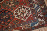 Distressed Baktiari rug detail with geometric panels and blossoming floral designs in rich hues.