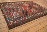 Distressed vintage Baktiari rug side, displaying hexagonal floral panels, rich colors, and worn edge.