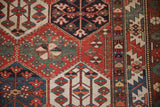 Distressed vintage Baktiari rug showing brick red, denim blue, mallard green floral geometric patterns.