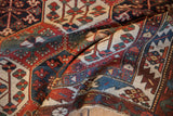 Distressed Baktiari rug detail with aubergine red, cream, blue blossoming floral motifs.