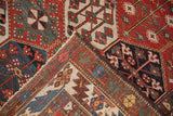 Distressed Baktiari rug's folded corner, showing hand-knotted structure, red-blue palette, and floral motifs.