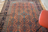 Distressed vintage Malayer rug featuring intricate brick red field and repeating sky blue herati patterns.