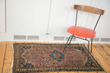 Tattered ends and worn side of a vintage distressed Malayer rug.