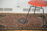 Distressed vintage Malayer rug showcasing dusty rose herati field and geometric blue designs.