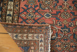 Distressed Malayer rug corner, revealing its hand-knotted back and tattered edge.