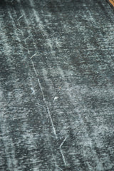 Textured dark gray overdyed surface with acid wash effect on a vintage rug.