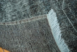 Hand-knotted vintage overdyed rug's distressed black pile, showing light blue fringe and tight reverse weave.
