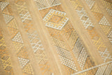 Close-up of geometric patterns in saffron, ivory, and taupe on a Moroccan Kilim.