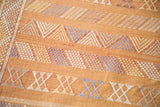 Detailed geometric stripes in faded blue, ivory, gold on burnt orange Moroccan kilim.