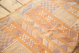 Finely woven geometric patterns and detailed embellishments on a burnt orange kilim.