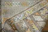 Close-up of finely woven kilim rug showing detailed gold, ivory, beige embroidered embellishments.