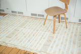 Hyper white Moroccan kilim rug with geometric stripes in saffron, blue, and mauve.