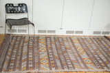 Eggplant purple embroidered kilim rug with geometric stripes in gold, ivory, and beige.