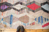 Textured argyle diamond motif with colorful woven strips on vintage Moroccan rag rug.