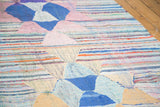 Dense woven texture, with geometric blue, pink, and orange patterns on a vintage rag rug.