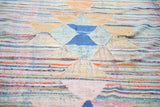 Dense woven texture of vintage rag rug featuring geometric blue, orange, and ivory triangles.