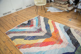 Angular pattern of colorful recycled textile strips on a vintage Moroccan rag rug.