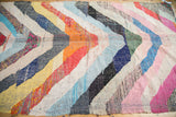Vibrant zigzag pattern of orange, blue, pink, and red on a vintage Moroccan rag rug.