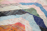 Detail of chunky woven vintage Moroccan rag rug in blue, pink, and orange.