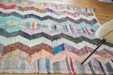 Textured woven strips forming a multi-color zigzag motif on a vintage rag rug.