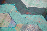 Interwoven textile strips of a vintage Moroccan rag rug, showing sky blue, charcoal, and ivory.