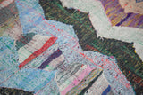 Close-up of vintage Moroccan rag rug, dense woven zigzag motif in blue, red, green.