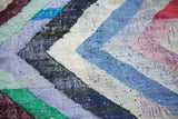 Dense, hand-woven texture of the rag rug, displaying a vibrant zigzag pattern in blue, ivory, and violet.
