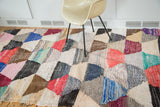 Angled detail of vintage rag rug with hexagonal motif, featuring varied textile texture and bright colors.