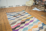 Vintage rag rug displaying striped ends and colorful diagonal motif in tangerine, blue, purple.