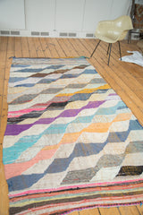 Woven vintage rag rug detail showing dense, vibrant diagonal motif and striped end.