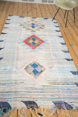 Geometric medallion in blush, blue, gold, and purple on vintage Moroccan rag rug texture.