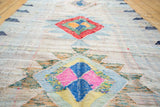 Textured geometric medallion in pink, blue, yellow on a vintage Moroccan rag rug.