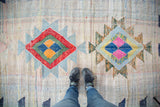 Dense woven texture of vintage Moroccan rag rug with two colorful geometric medallions.