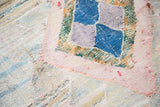 Textured surface of a vintage rag rug showing pink and blue geometric weave.