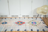 Geometric pink, blue, yellow medallion and denim accents on vintage Moroccan rag rug texture.