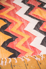 Vintage rag rug with faded tangerine, brick red, charcoal zig-zag chevron and fringe.