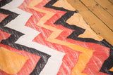 Woven texture and geometric zig-zag motif of the Moroccan rag rug in off-white, tangerine, and black.