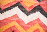 Vintage Moroccan geometric rag rug close-up: woven zig-zag in faded orange, red, black, off-white.