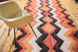 Faded tangerine, brick red, charcoal black, and off-white zig-zag diamond pattern.
