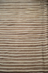 Striated handwoven flatweave of a vintage Moroccan Kilim rug, showing natural undyed tones.