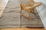 Moroccan Kilim rug with natural ivory, coffee, charcoal striped pattern and burgundy overcast.
