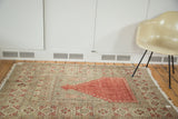 Distressed cinnabar red prayer design and patterned borders of this vintage Oushak rug.