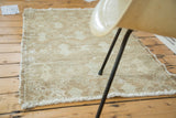 Faded celadon and natural brown tones on a distressed Oushak rug's edge, foundation visible.