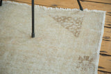 Distressed blanched Oushak rug corner, showing subtle ivory pile and coffee spandrel design.