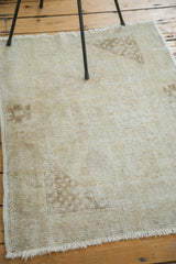Fringed corner of a vintage Oushak rug, showing distressed blanched pile and light coffee spandrel.