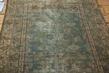 Heavily distressed texture of a vintage Malayer rug, showing faded green field and patterned border.