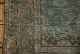 Stylized leaf and vine border of a distressed vintage Malayer rug, muted green and brown tones.
