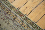 Distressed Oushak rug's secured border with faded moss green, saffron, and purple patterns.